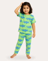Child wearing green pajamas with blue alligator prints on a white background
